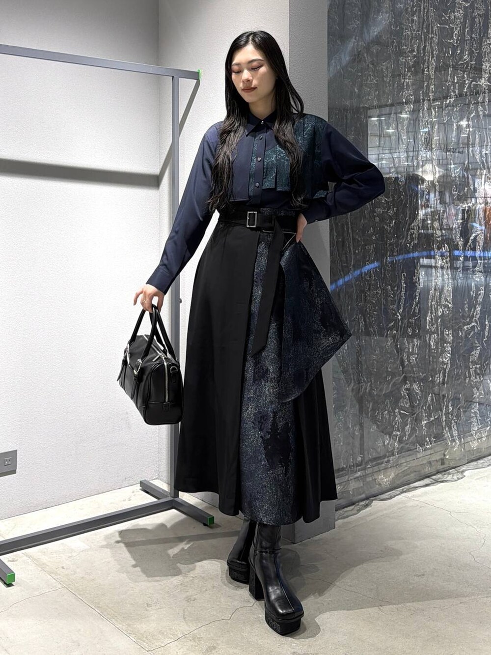 ブラック系のボストンバッグ、ブラック系のブーツ、グリーン系のスカートを着用したレディースの冬コーディネートの4枚目の写真