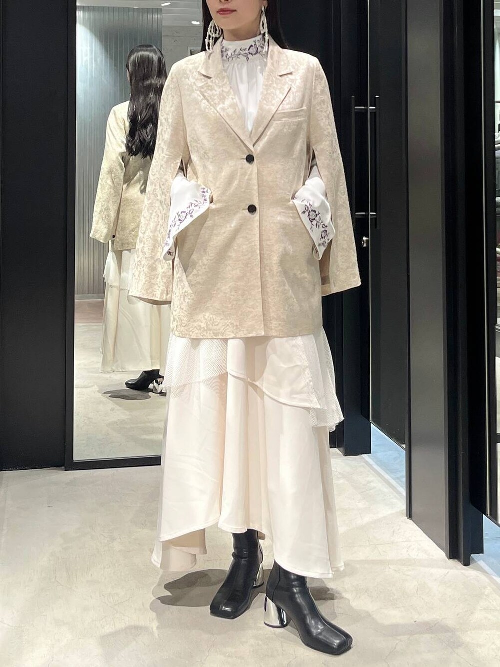 ブラック系のブーツ、ホワイト系のシャツ/ブラウス、ホワイト系のテーラードジャケットを着用したレディースの冬コーディネートの2枚目の写真