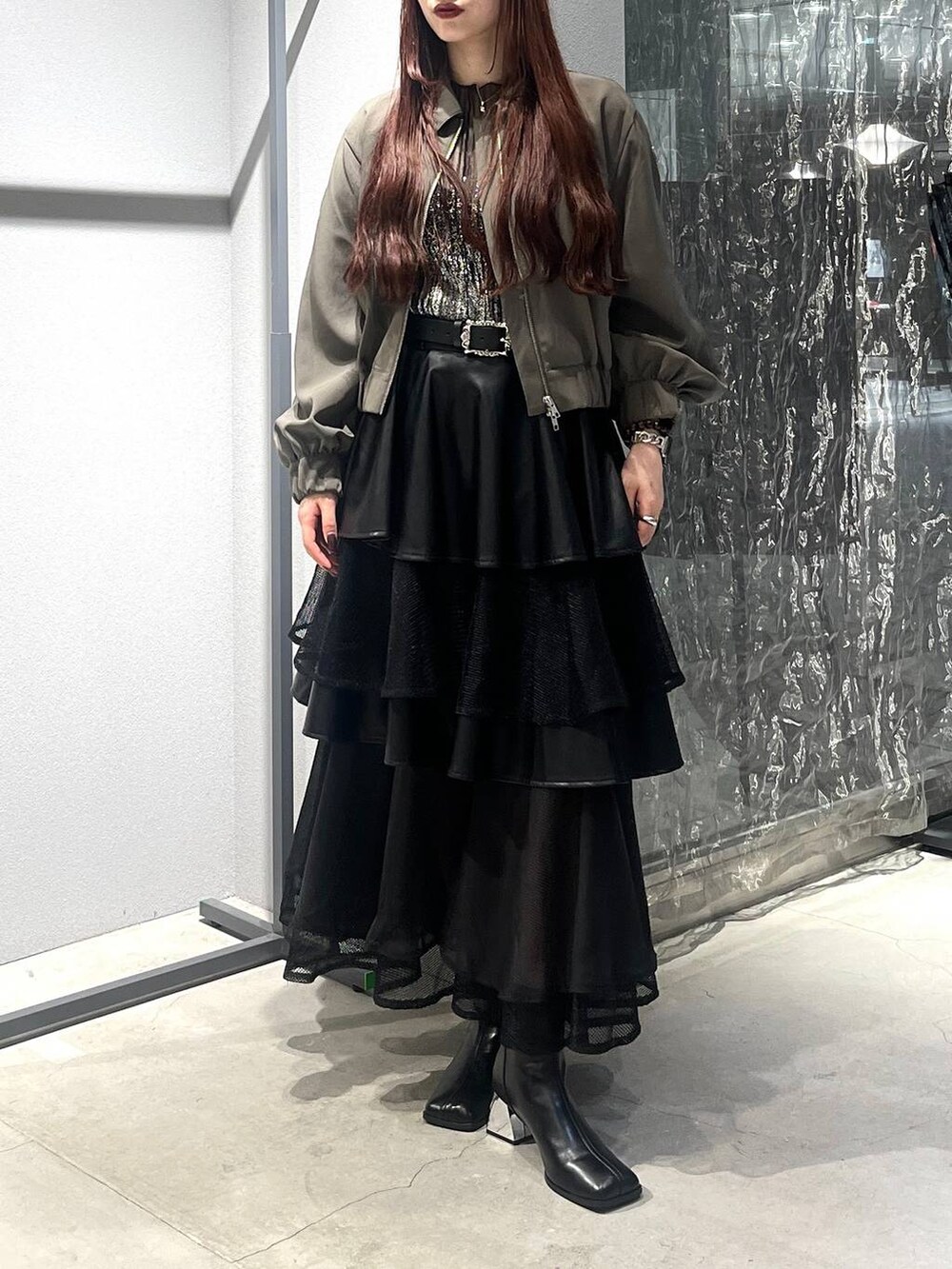 ブラック系のスカート、ベージュ系のブルゾン、ブラック系のブーツを着用したレディースの夏コーディネートの5枚目の写真