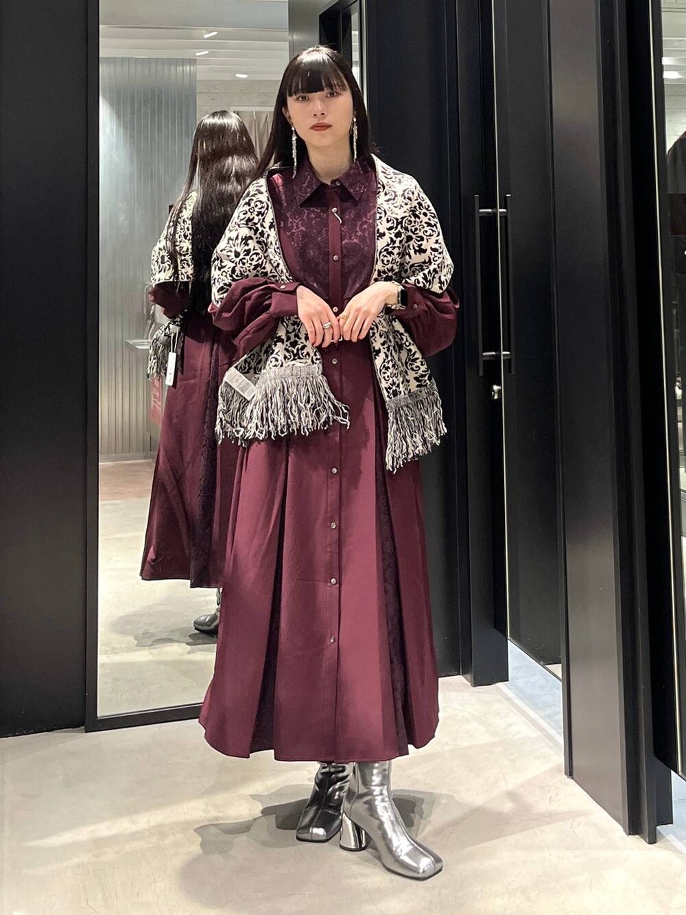 シルバー系のブーツ、レッド系のワンピース、ブラック系のマフラーを着用したレディースの秋コーディネートの5枚目の写真