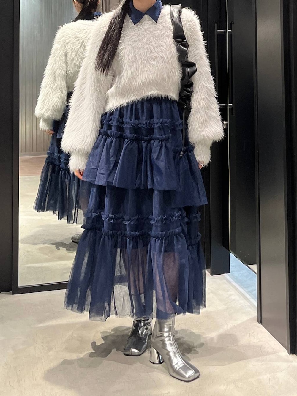 グレー系のニット/セーター、シルバー系のブーツ、ブルー系のシャツ/ブラウスを着用したレディースの秋コーディネートの2枚目の写真