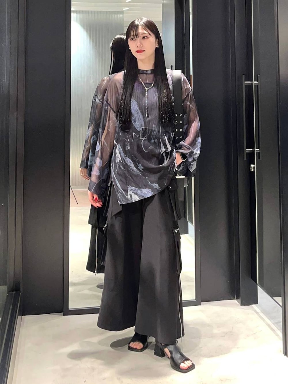 ブラック系のカーゴパンツ、ブラック系のショルダーバッグ、ブラック系のサンダルを着用したレディースの春コーディネートの2枚目の写真