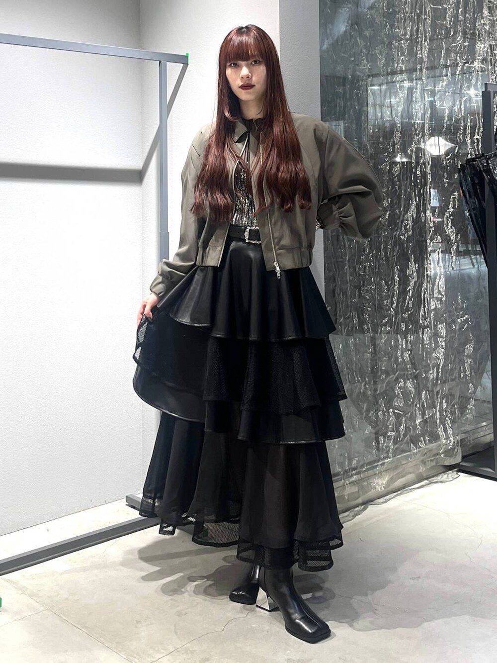 ブラック系のスカート、ベージュ系のブルゾン、ブラック系のブーツを着用したレディースの夏コーディネートの2枚目の写真