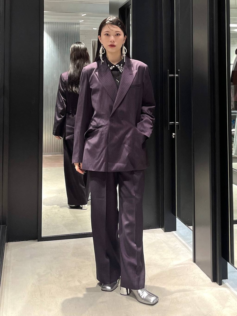 シルバー系のブーツ、ブラック系のシャツ/ブラウス、パープル系のスラックスを着用したレディースの秋コーディネートの2枚目の写真