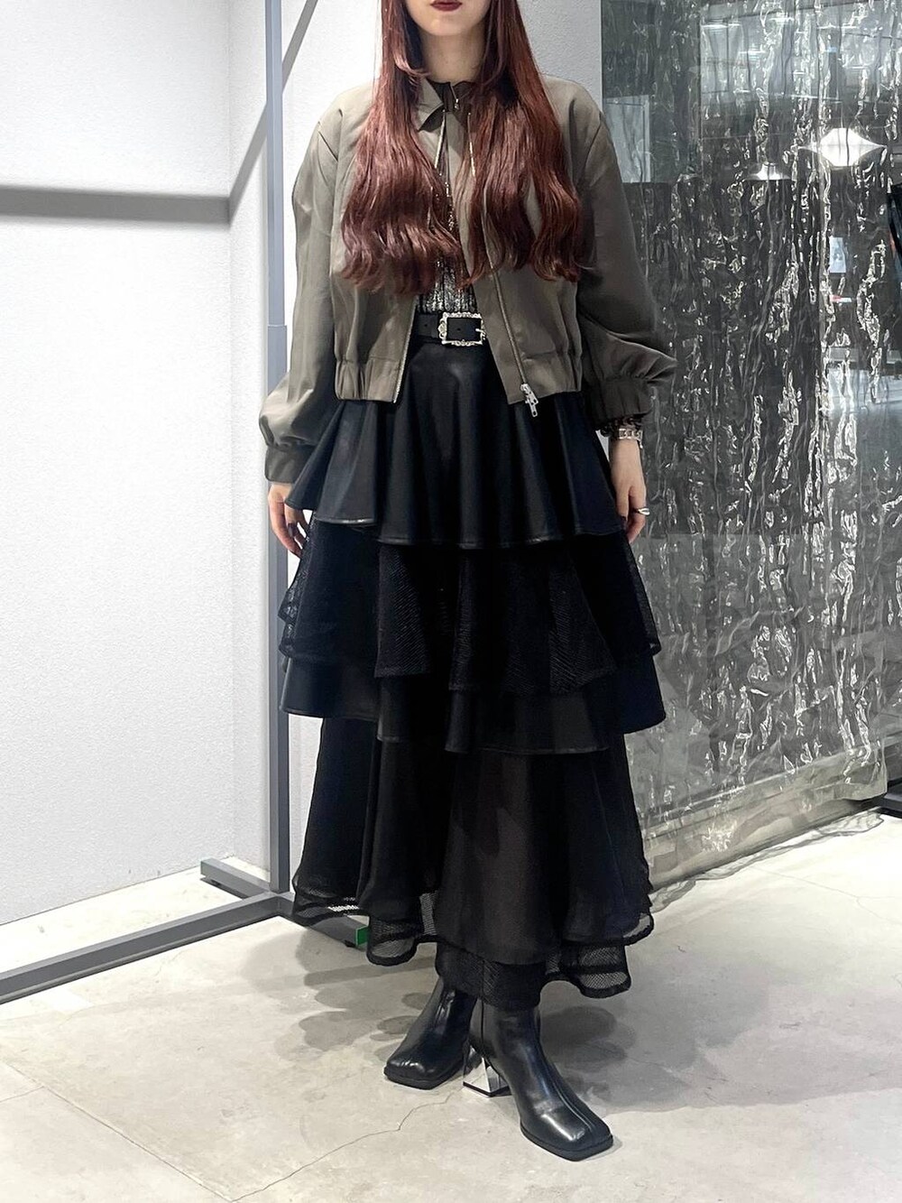 ブラック系のスカート、ベージュ系のブルゾン、ブラック系のブーツを着用したレディースの夏コーディネートの7枚目の写真
