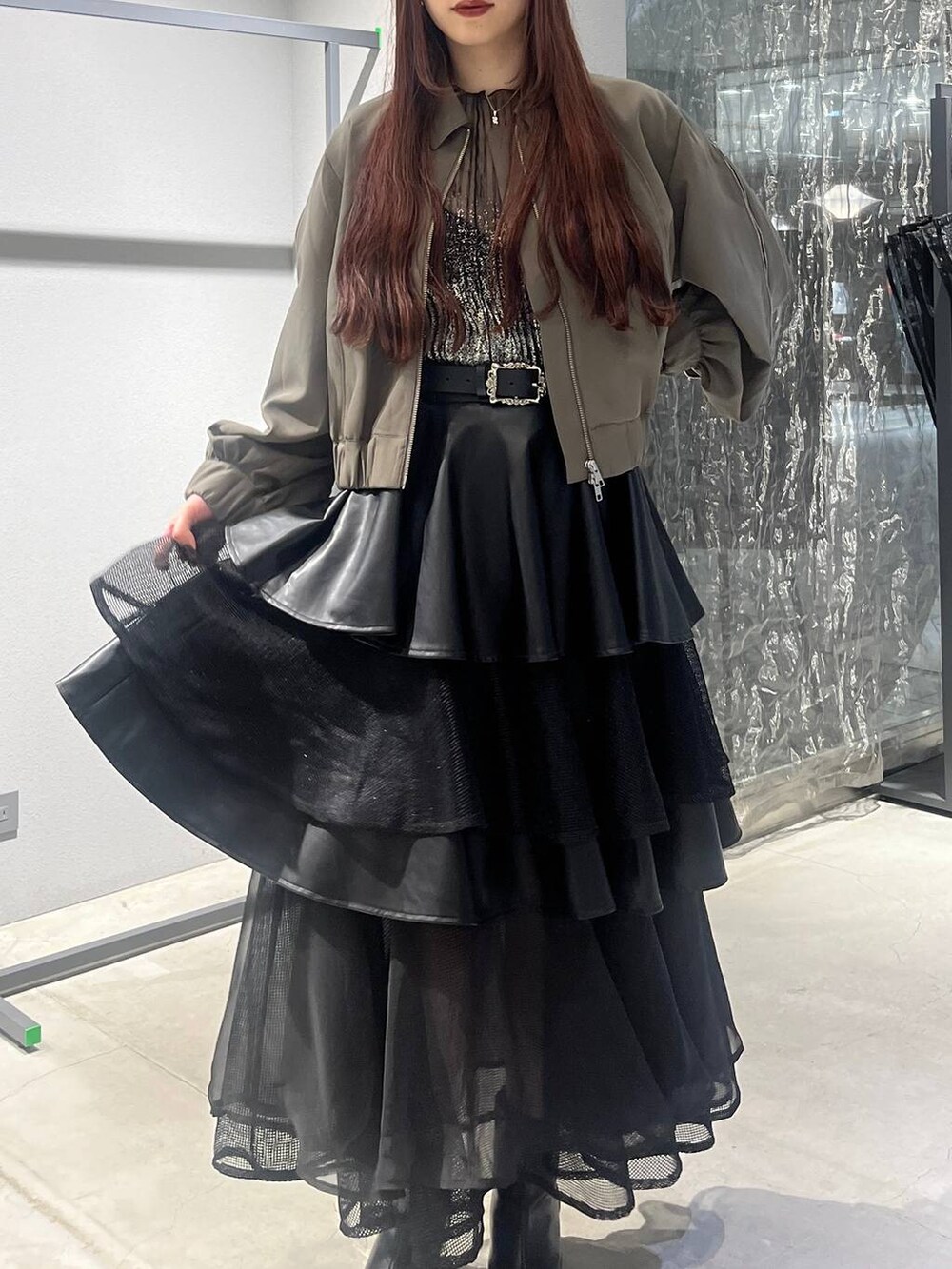 ブラック系のスカート、ベージュ系のブルゾン、ブラック系のブーツを着用したレディースの夏コーディネートの6枚目の写真