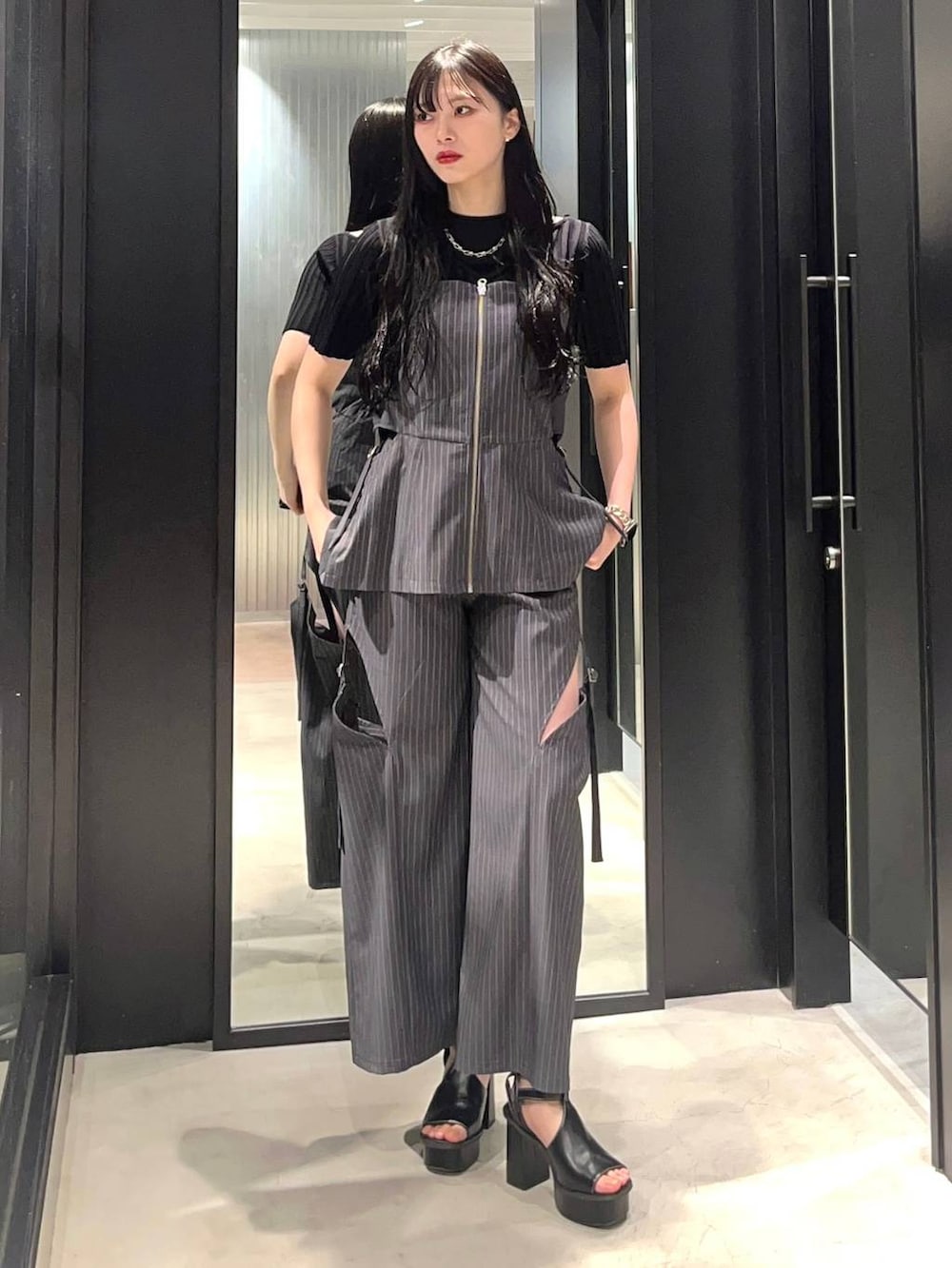 ブラック系のサンダル、ブラック系のニット/セーター、グレー系のベストを着用したレディースの春コーディネートの2枚目の写真