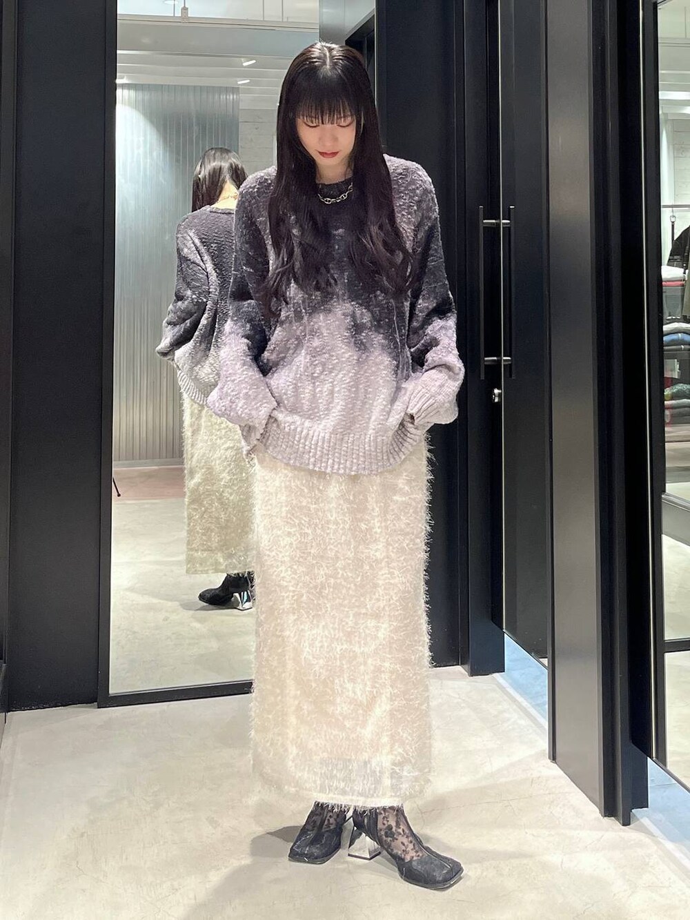 ブラック系のブーツ、ホワイト系のスカート、ブラック系のニット/セーターを着用したレディースの冬コーディネートの3枚目の写真