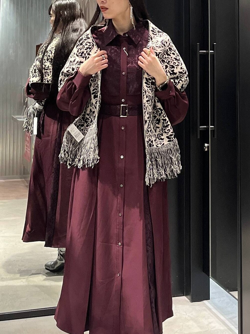 シルバー系のブーツ、レッド系のワンピース、ブラック系のマフラーを着用したレディースの秋コーディネートの4枚目の写真