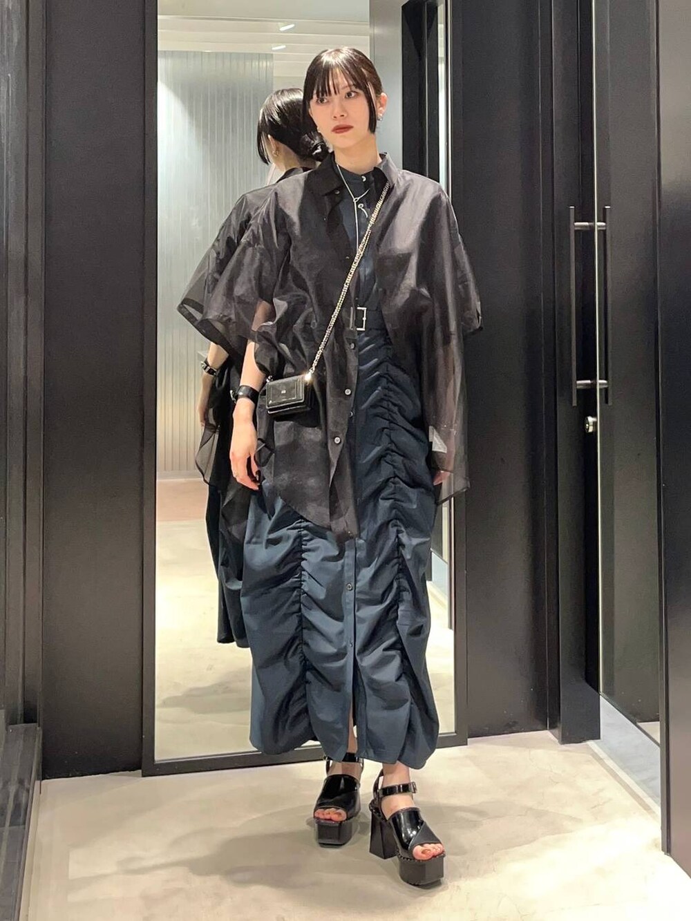 ブラック系のサンダル、ブラック系のシャツ/ブラウス、グリーン系のワンピースを着用したレディースの春コーディネートの2枚目の写真