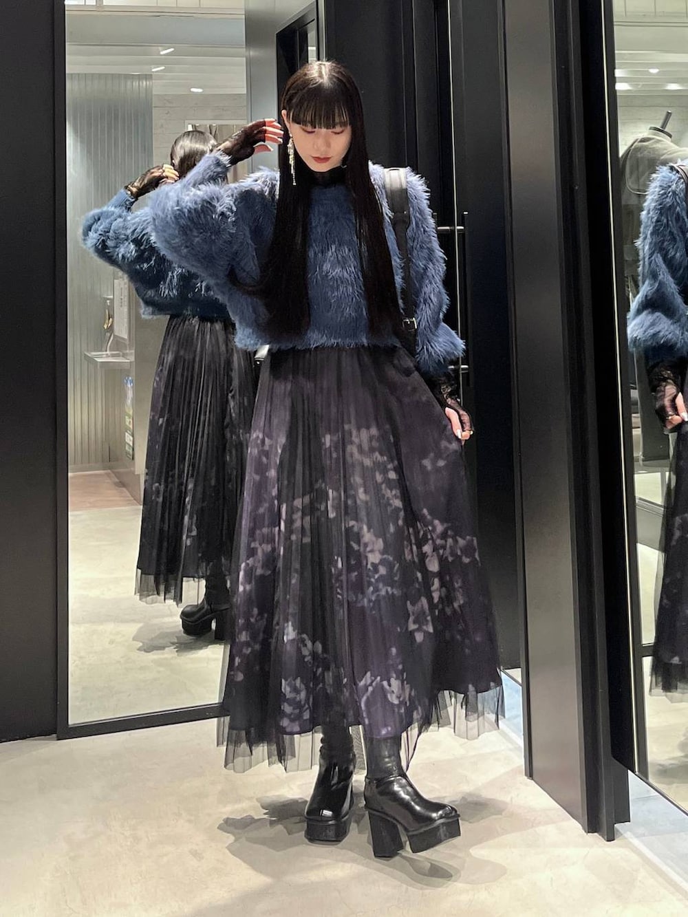 ブルー系のニット/セーター、ブラック系のブーツ、ブラック系のショルダーバッグを着用したレディースの秋コーディネートの5枚目の写真