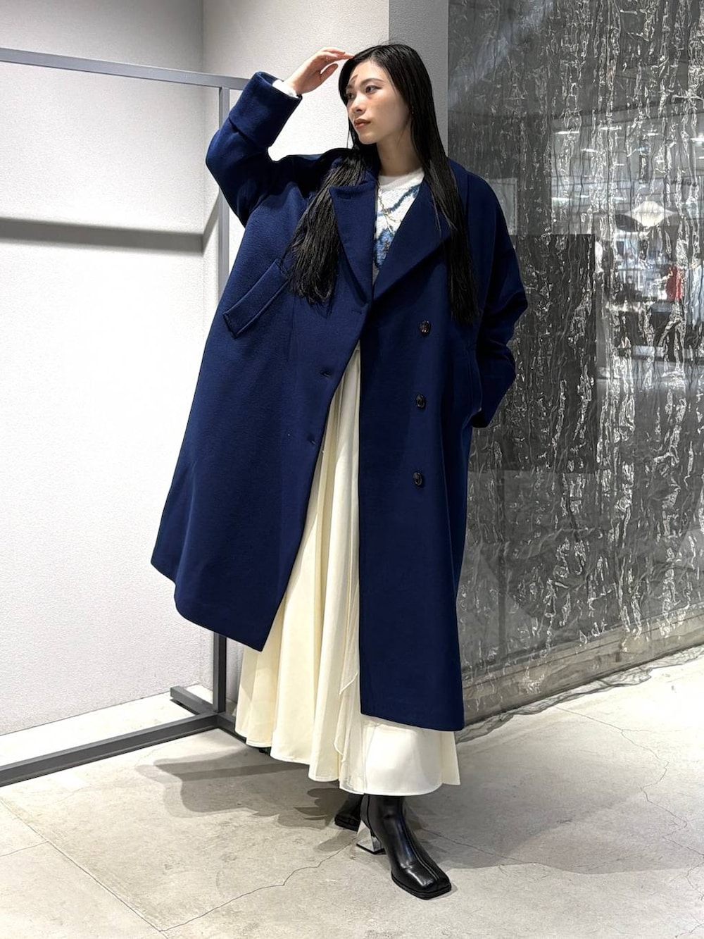 ブルー系のチェスターコート、ブラック系のブーツ、ホワイト系のスカートを着用したレディースの秋コーディネートの3枚目の写真