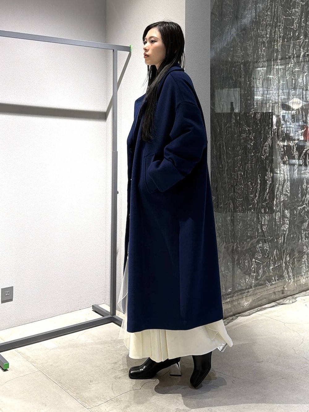 ブルー系のチェスターコート、ブラック系のブーツ、ホワイト系のスカートを着用したレディースの秋コーディネートの2枚目の写真