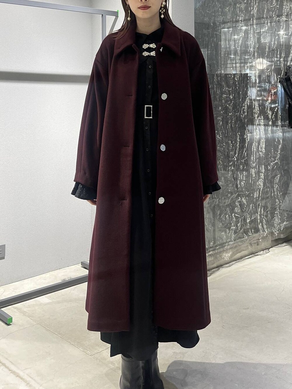 レッド系のステンカラーコート、ブラック系のブーツ、ブラック系のワンピースを着用したレディースの秋コーディネートの7枚目の写真