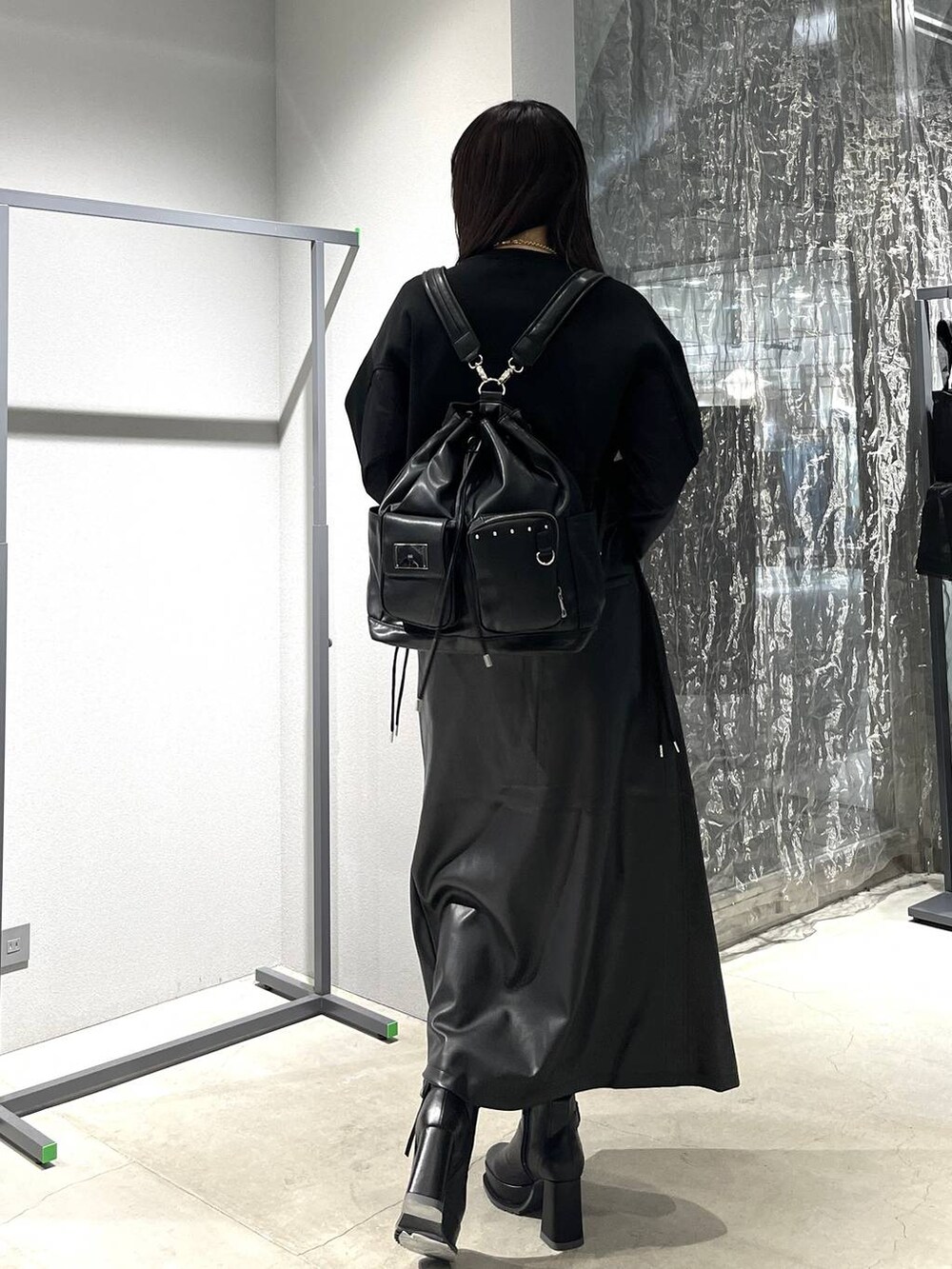 ブラック系のバックパック/リュック、ブラック系のスカート、ブラック系のブーツを着用したレディースの秋コーディネートの5枚目の写真