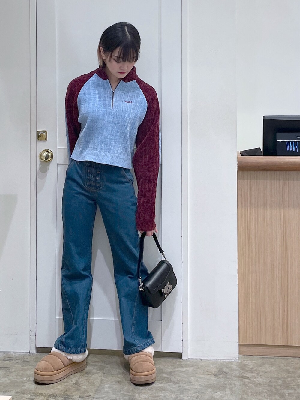 レッド系のニット/セーター、ブルー系のデニムパンツ、ブラック系のショルダーバッグを着用したメンズの冬コーディネートの2枚目の写真