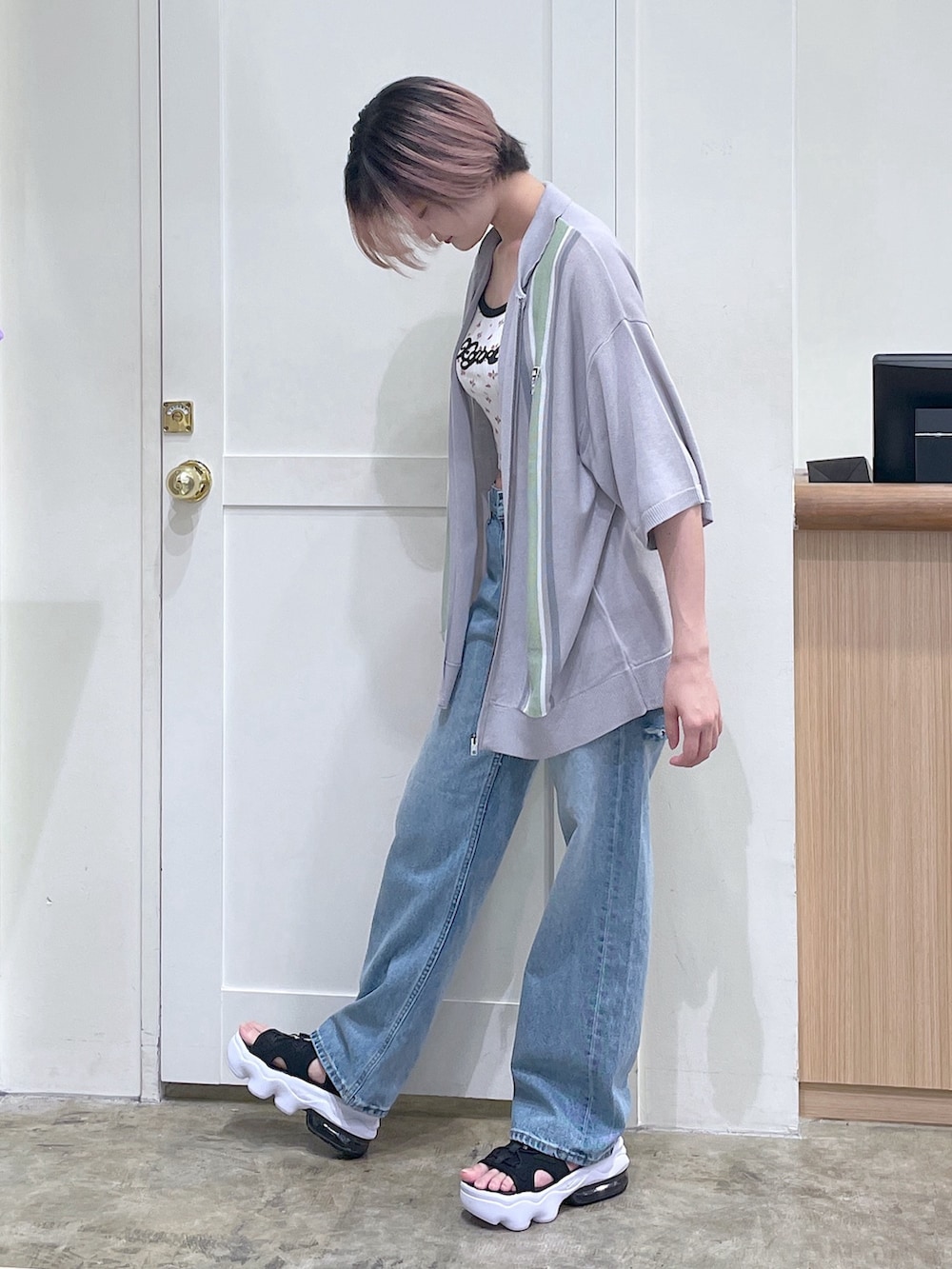 グレー系のポロシャツ、ホワイト系のキャミソール、ブルー系のデニムパンツを着用したメンズの夏コーディネートの2枚目の写真