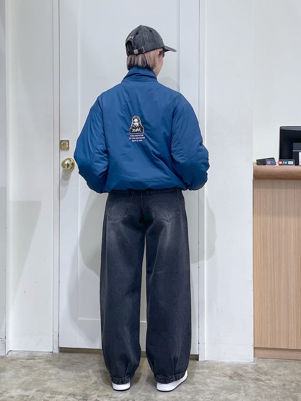 ブルー系のナイロンジャケット、ブラック系のデニムパンツ、ブラック系のキャップを着用したメンズの秋コーディネートの3枚目の写真