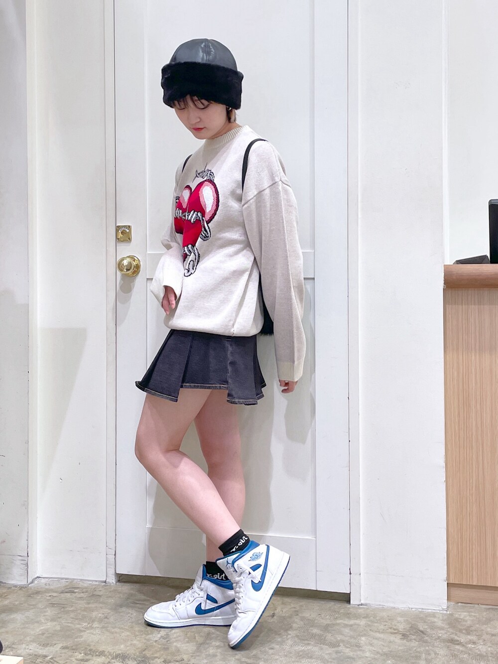 ホワイト系のニット/セーター、ブラック系のバックパック/リュック、ブラック系のデニムスカートを着用したメンズの秋コーディネートの3枚目の写真