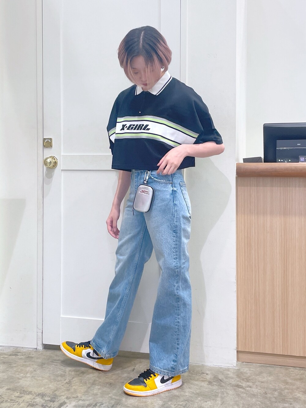 ブラック系のポロシャツ、ブルー系のデニムパンツ、シルバー系のカードケースを着用したメンズの夏コーディネートの2枚目の写真