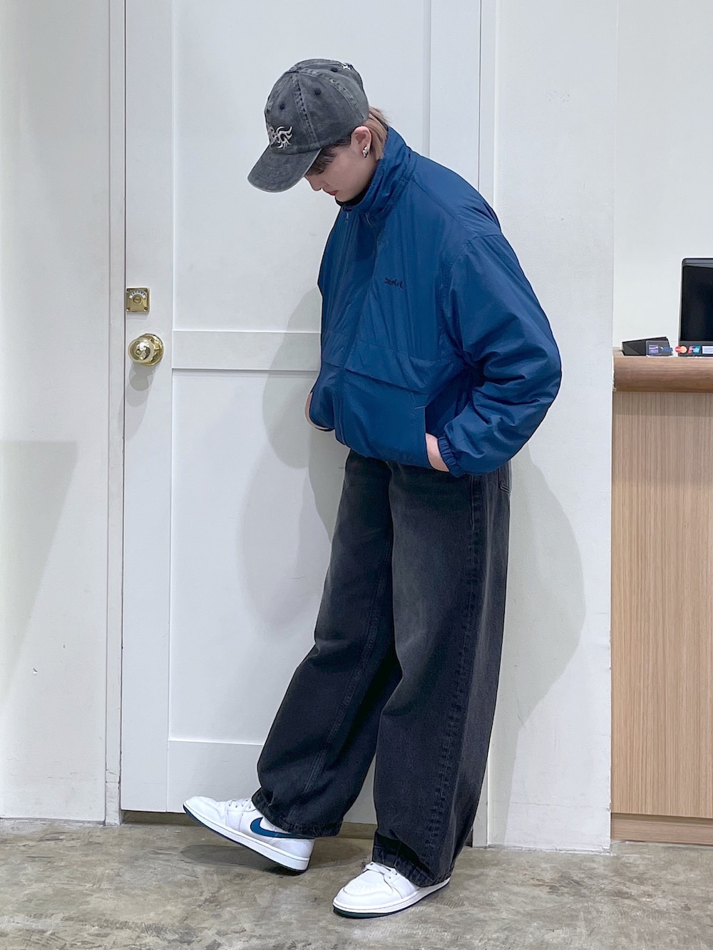 ブルー系のナイロンジャケット、ブラック系のデニムパンツ、ブラック系のキャップを着用したメンズの秋コーディネートの2枚目の写真