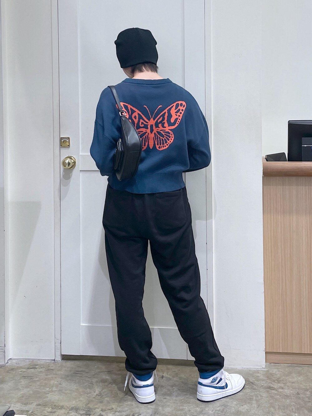 ブルー系のニット/セーター、ブラック系のスウェットパンツ、シルバー系のハンドバッグを着用したメンズの秋コーディネートの3枚目の写真