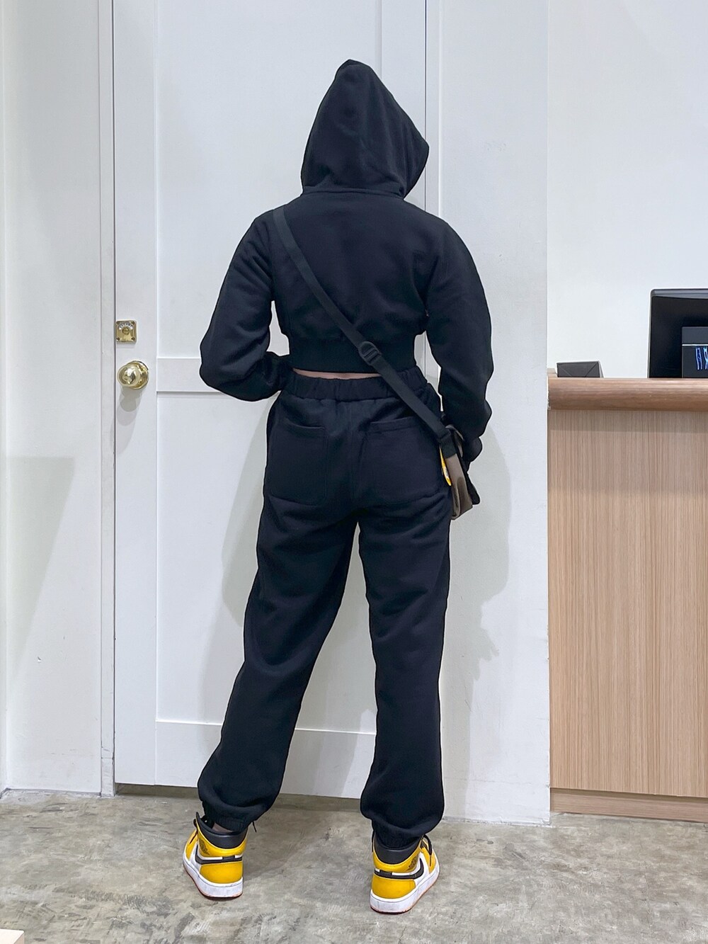 ブラック系のスウェットパンツ、ブラック系のパーカー、グリーン系のショルダーバッグを着用したレディースの春コーディネートの3枚目の写真