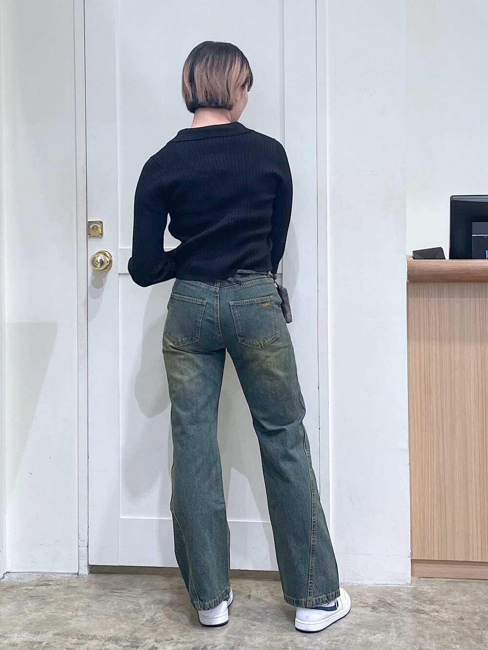 ブラック系のニット/セーター、ブルー系のデニムパンツ、ゴールド系のコインケースを着用したメンズの秋コーディネートの3枚目の写真