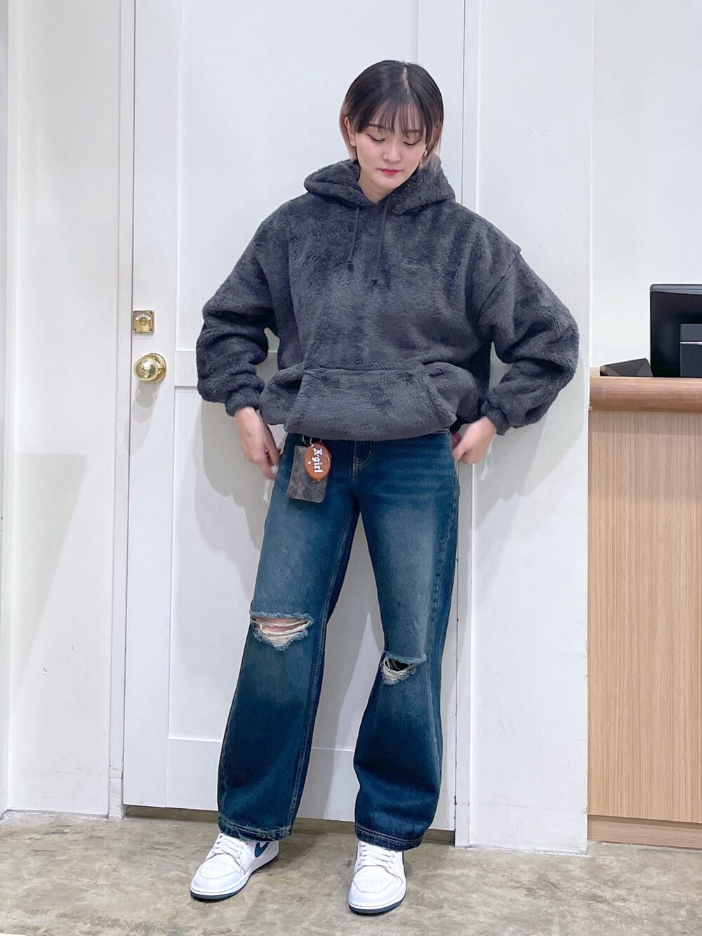 グレー系のパーカー、ブルー系のデニムパンツ、ゴールド系のコインケースを着用したメンズの秋コーディネートの2枚目の写真