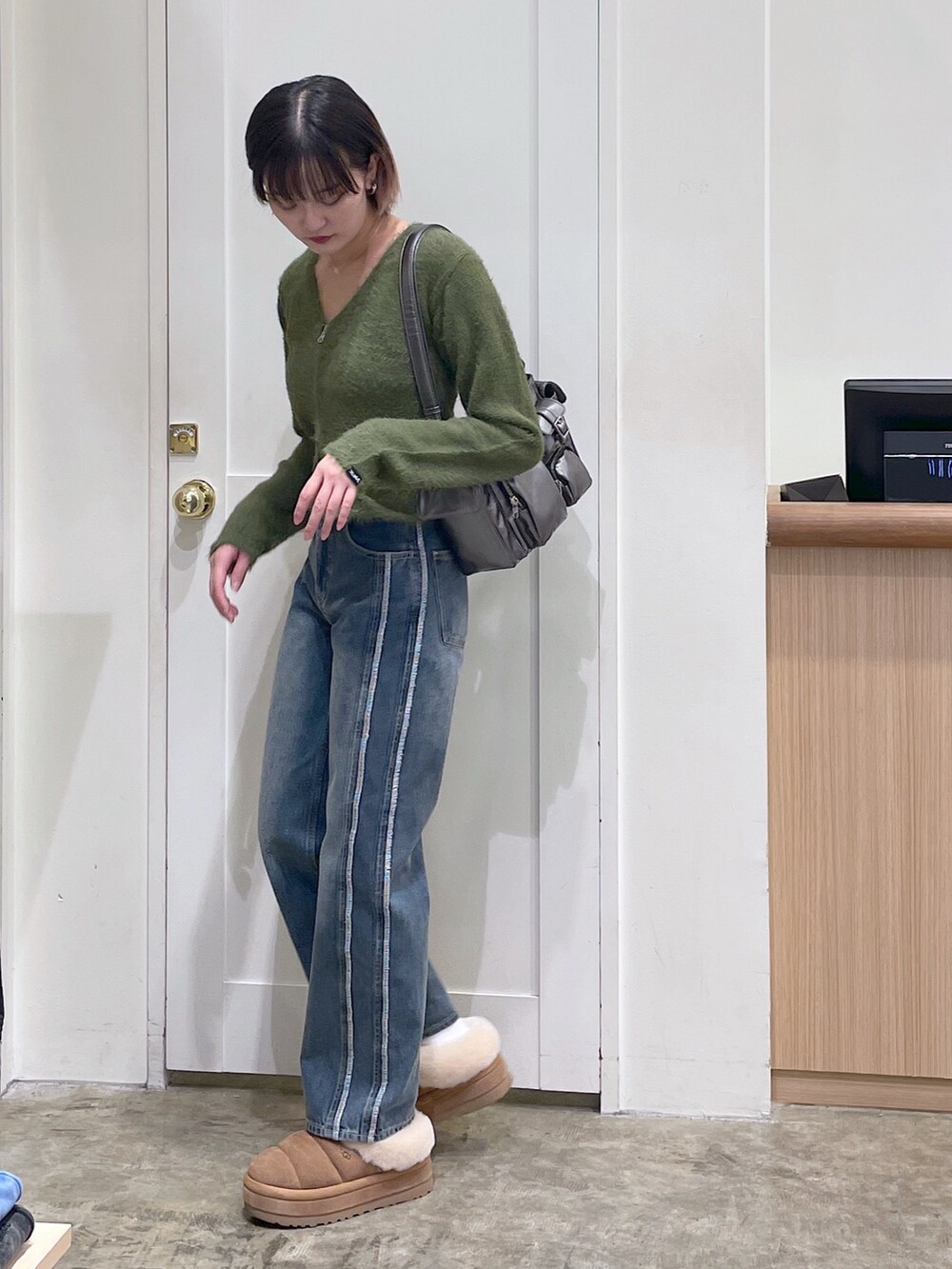 グリーン系のカーディガン/ボレロ、ブルー系のデニムパンツ、グレー系のハンドバッグを着用したメンズの秋コーディネートの2枚目の写真