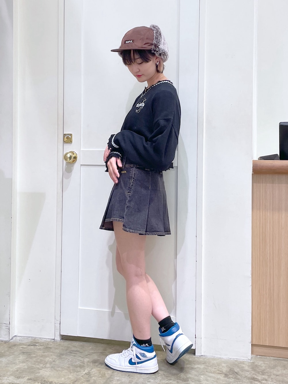 ブラック系のニット/セーター、ブラック系のデニムスカート、ブラウン系のキャップを着用したメンズの秋コーディネートの2枚目の写真