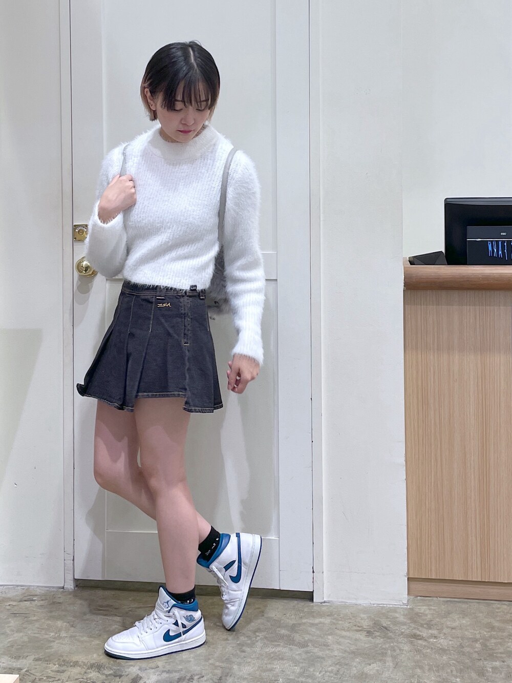 ホワイト系のニット/セーター、グレー系のバックパック/リュック、ブラック系のデニムスカートを着用したメンズの秋コーディネートの2枚目の写真