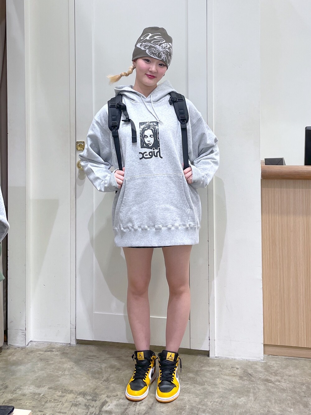 グレー系のパーカー、ブラック系のバックパック/リュック、グリーン系のニットキャップ/ビーニーを着用したレディースの春コーディネートの3枚目の写真