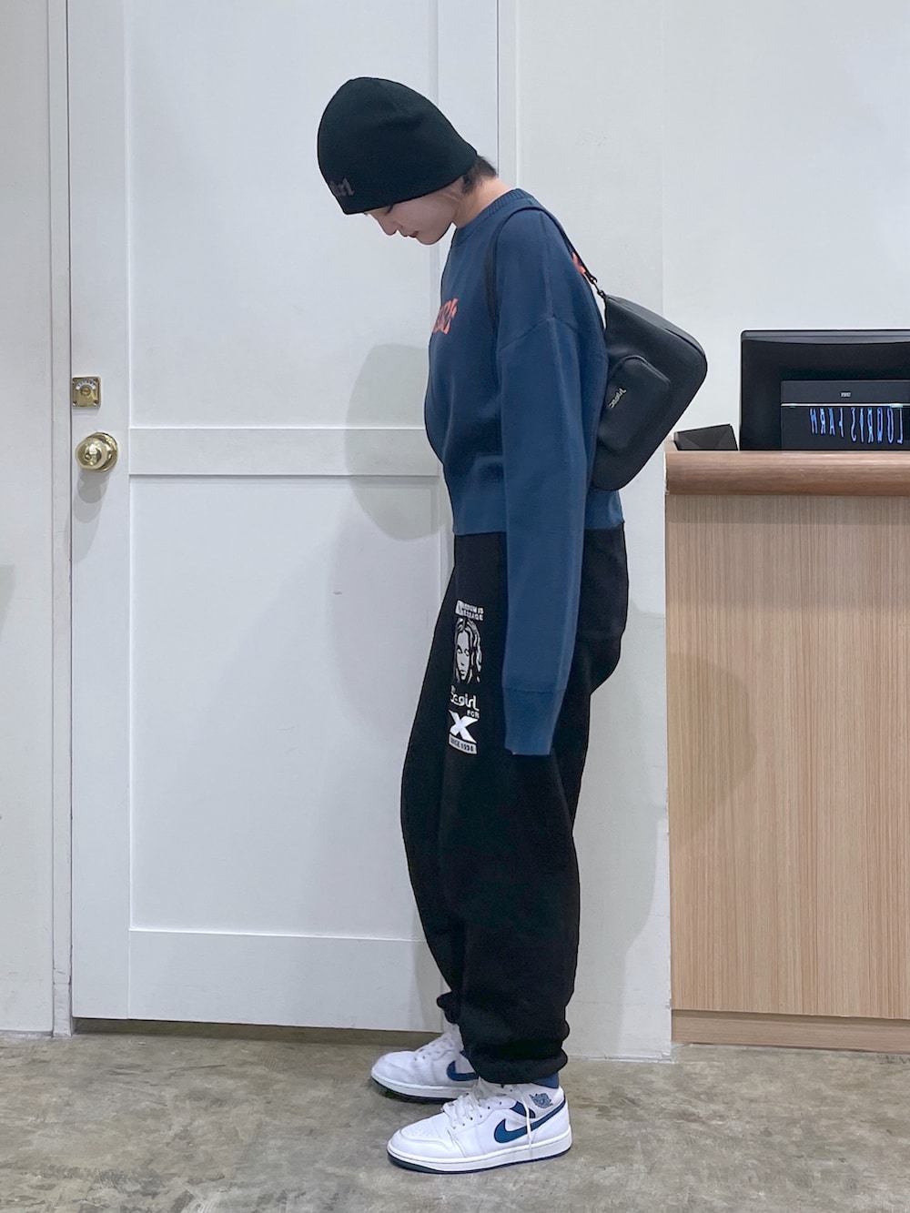 ブルー系のニット/セーター、ブラック系のスウェットパンツ、シルバー系のハンドバッグを着用したメンズの秋コーディネートの2枚目の写真