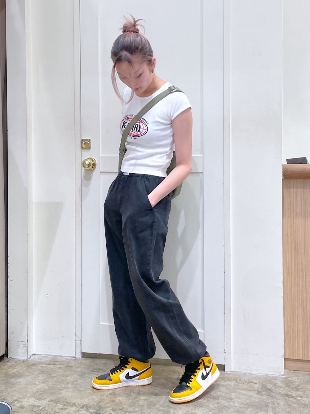 ブラック系のその他パンツ、ホワイト系のTシャツ/カットソー、グリーン系のショルダーバッグを着用したメンズの春コーディネートの2枚目の写真