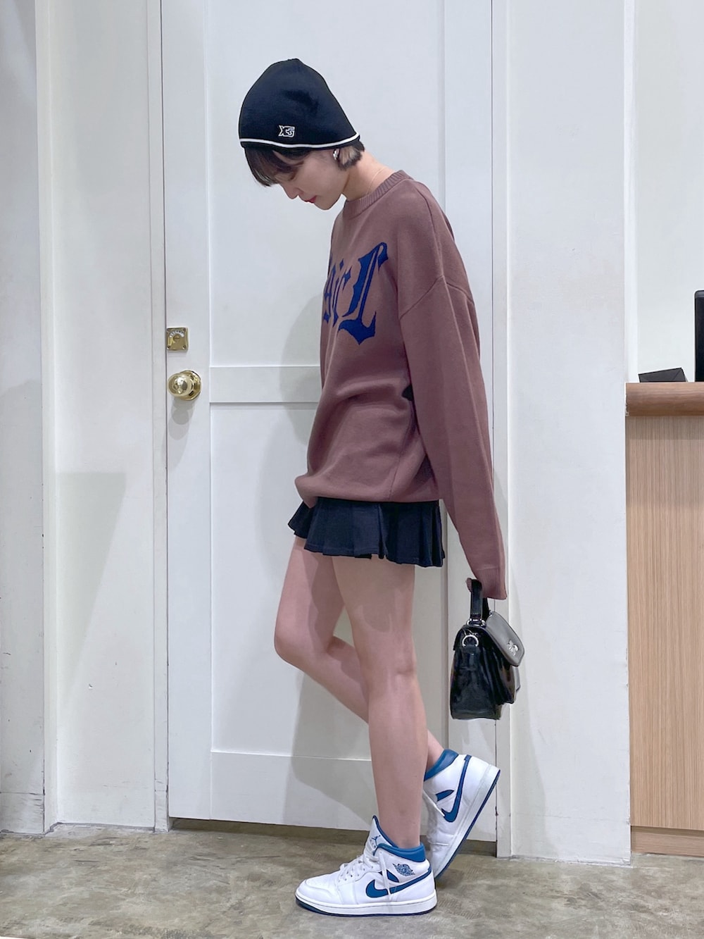 ブラウン系のニット/セーター、ブラック系のショルダーバッグ、ブラック系のスカートを着用したメンズの秋コーディネートの3枚目の写真