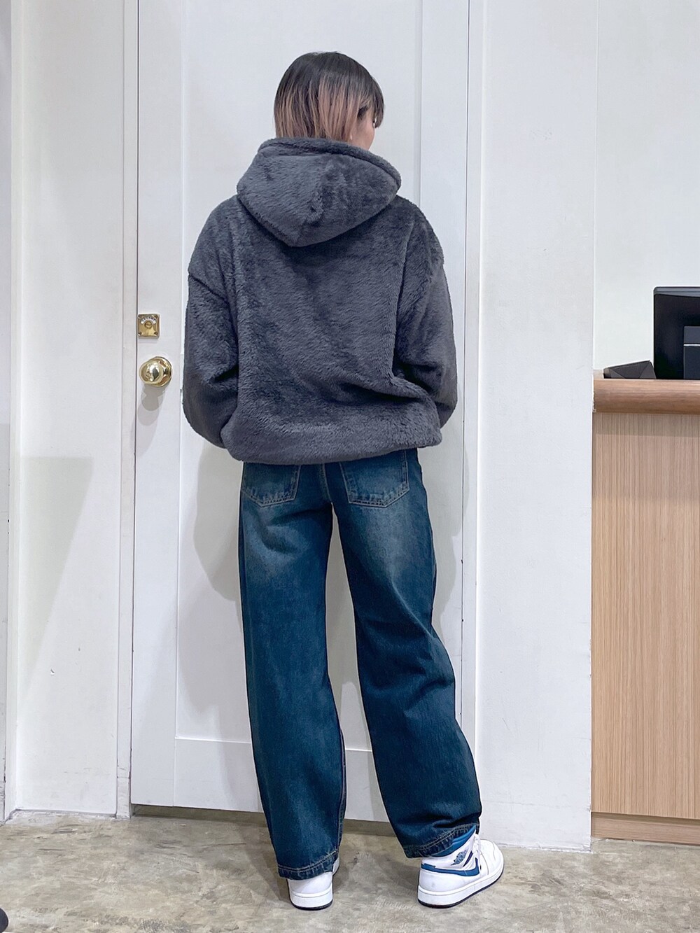 グレー系のパーカー、ブルー系のデニムパンツ、ゴールド系のコインケースを着用したメンズの秋コーディネートの3枚目の写真