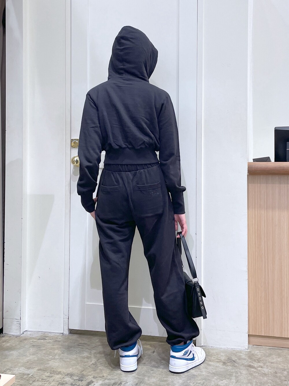 ブラック系のパーカー、ブラック系のスウェットパンツ、ブラック系のショルダーバッグを着用したメンズの秋コーディネートの3枚目の写真