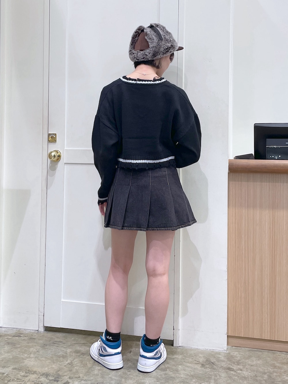 ブラック系のニット/セーター、ブラック系のデニムスカート、ブラウン系のキャップを着用したメンズの秋コーディネートの3枚目の写真