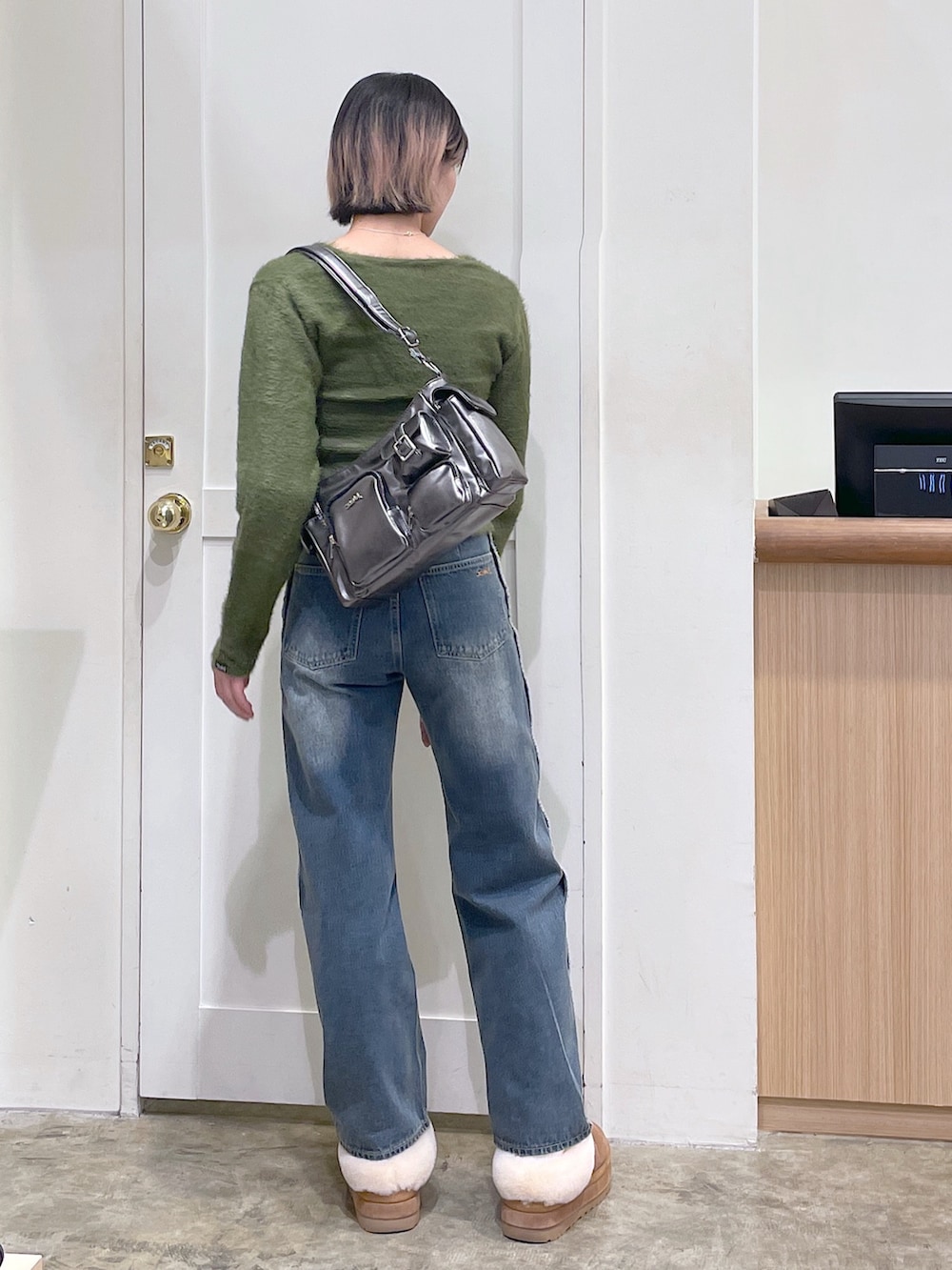 グリーン系のカーディガン/ボレロ、ブルー系のデニムパンツ、グレー系のハンドバッグを着用したメンズの秋コーディネートの3枚目の写真