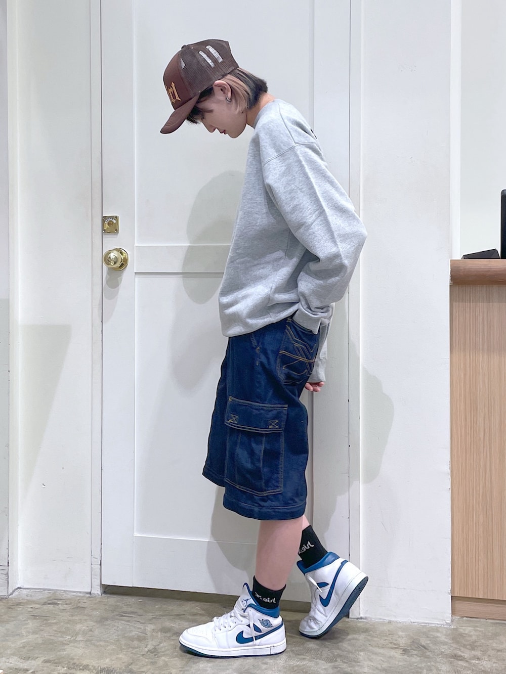 グレー系のスウェット、ブルー系のデニムパンツ、ブラウン系のキャップを着用したメンズの秋コーディネートの2枚目の写真