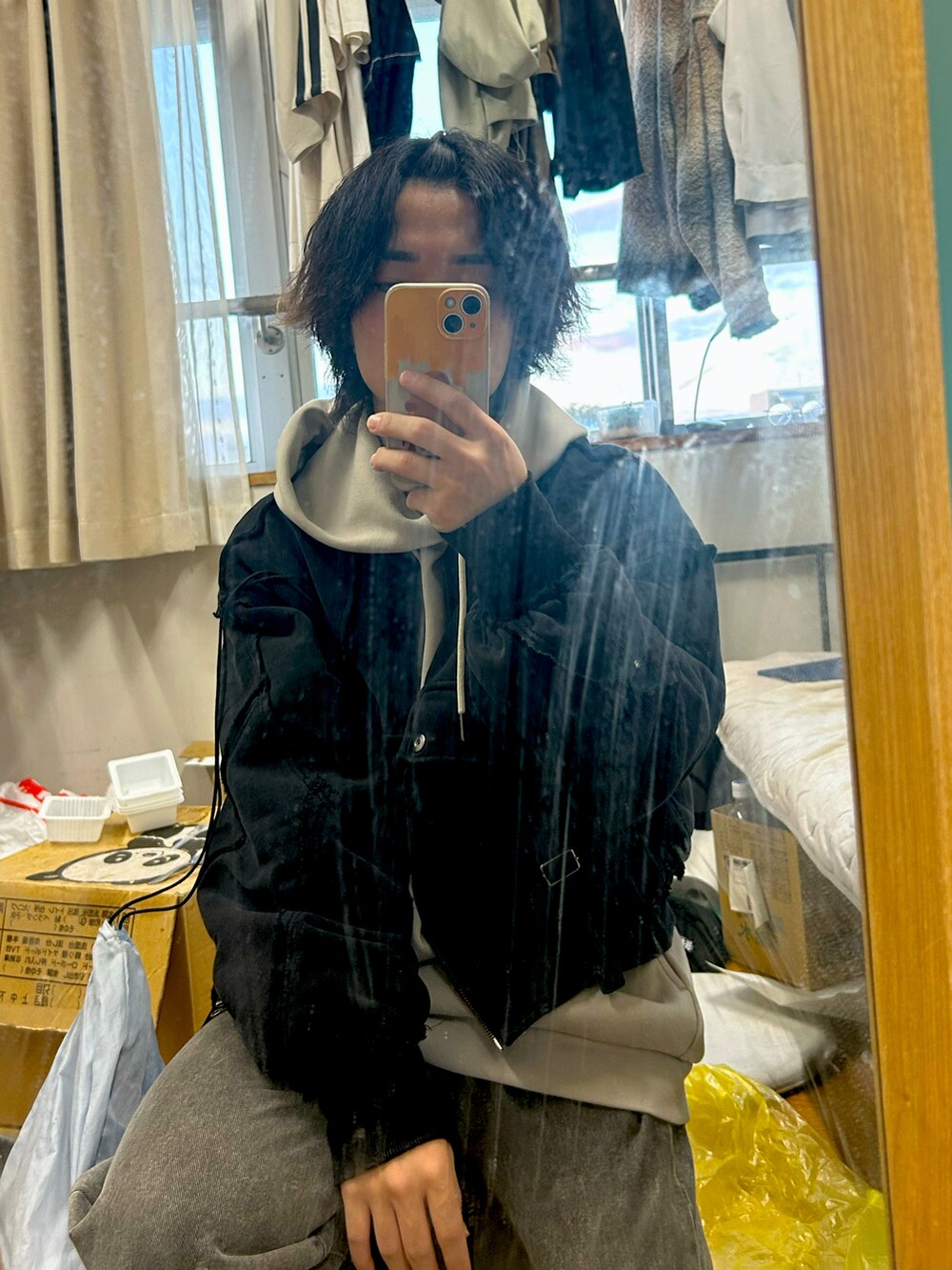 ブラック系のブルゾン、グレー系のデニムパンツ、ベージュ系のパーカーを着用したメンズの冬コーディネートの2枚目の写真