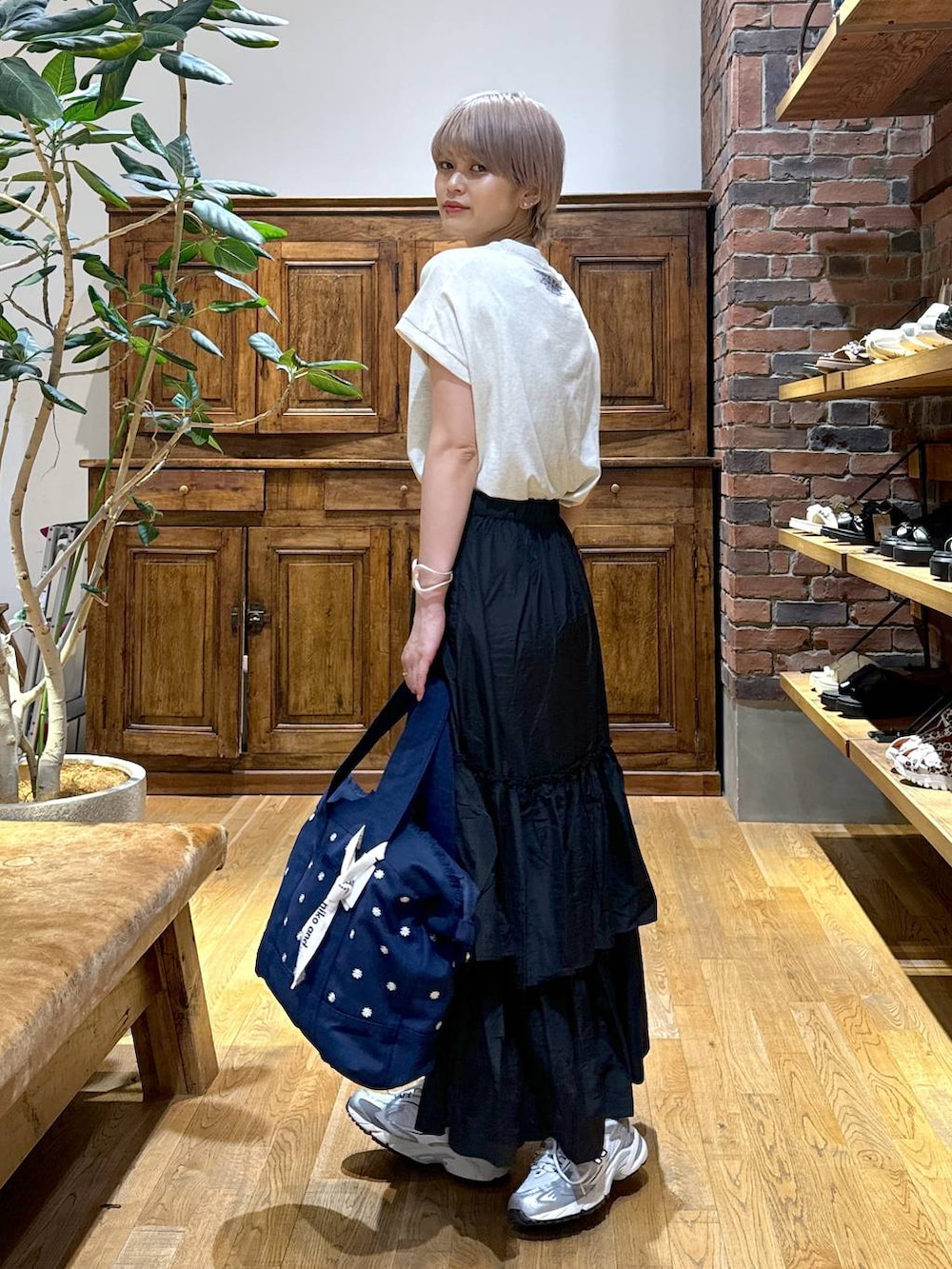 ブルー系のショルダーバッグ、グレー系のスニーカー、ブラック系のスカートを着用したレディースの夏コーディネートの2枚目の写真