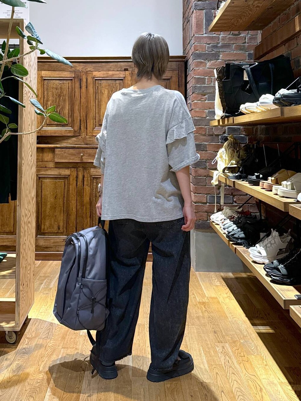 ブラック系のデニムパンツ、グレー系のバックパック/リュック、グレー系のTシャツ/カットソーを着用したレディースの夏コーディネートの3枚目の写真