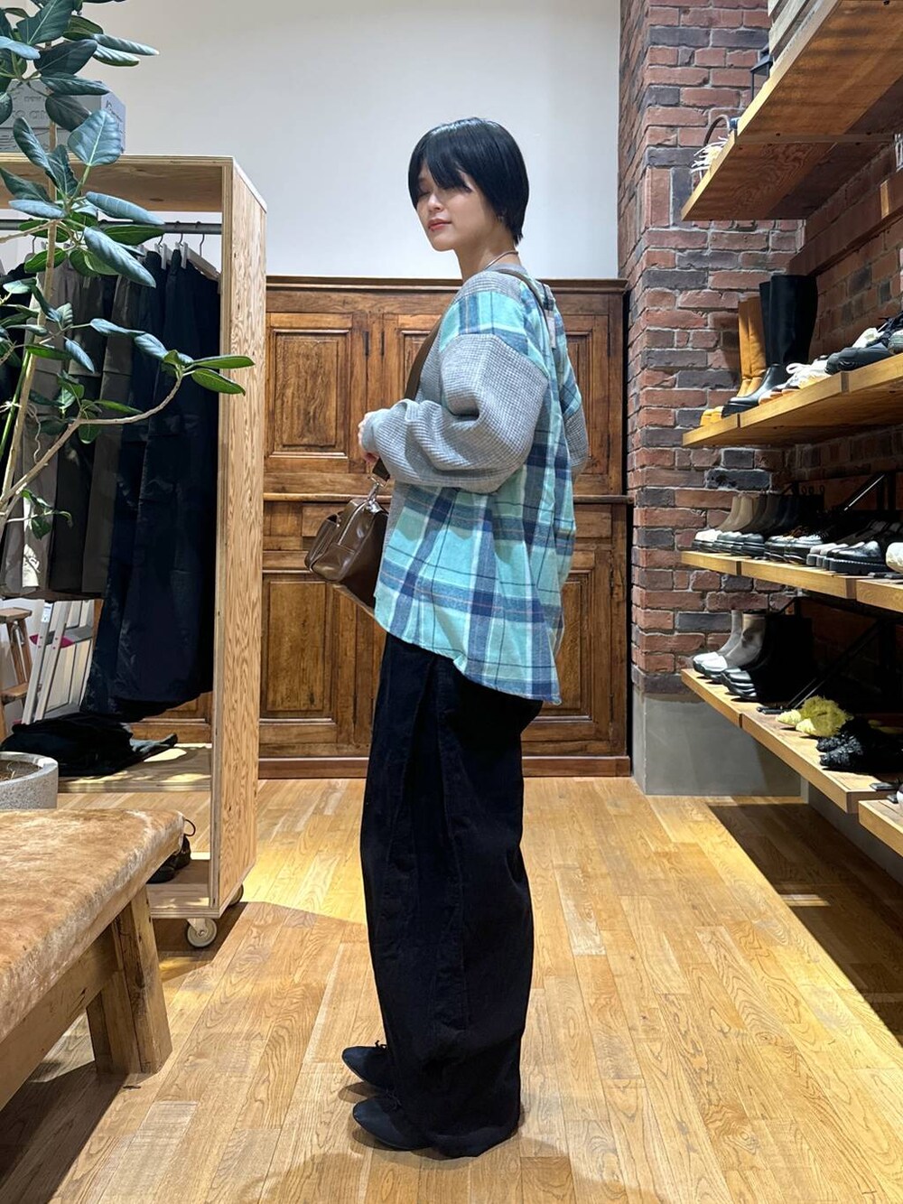 グレー系のスウェット、ブラック系のパンプス、ブラウン系のショルダーバッグを着用したレディースの秋コーディネートの6枚目の写真