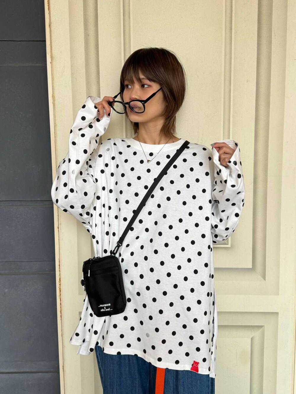 ブラック系のショルダーバッグ、ブルー系のデニムパンツ、ホワイト系のTシャツ/カットソーを着用したレディースの冬コーディネートの3枚目の写真