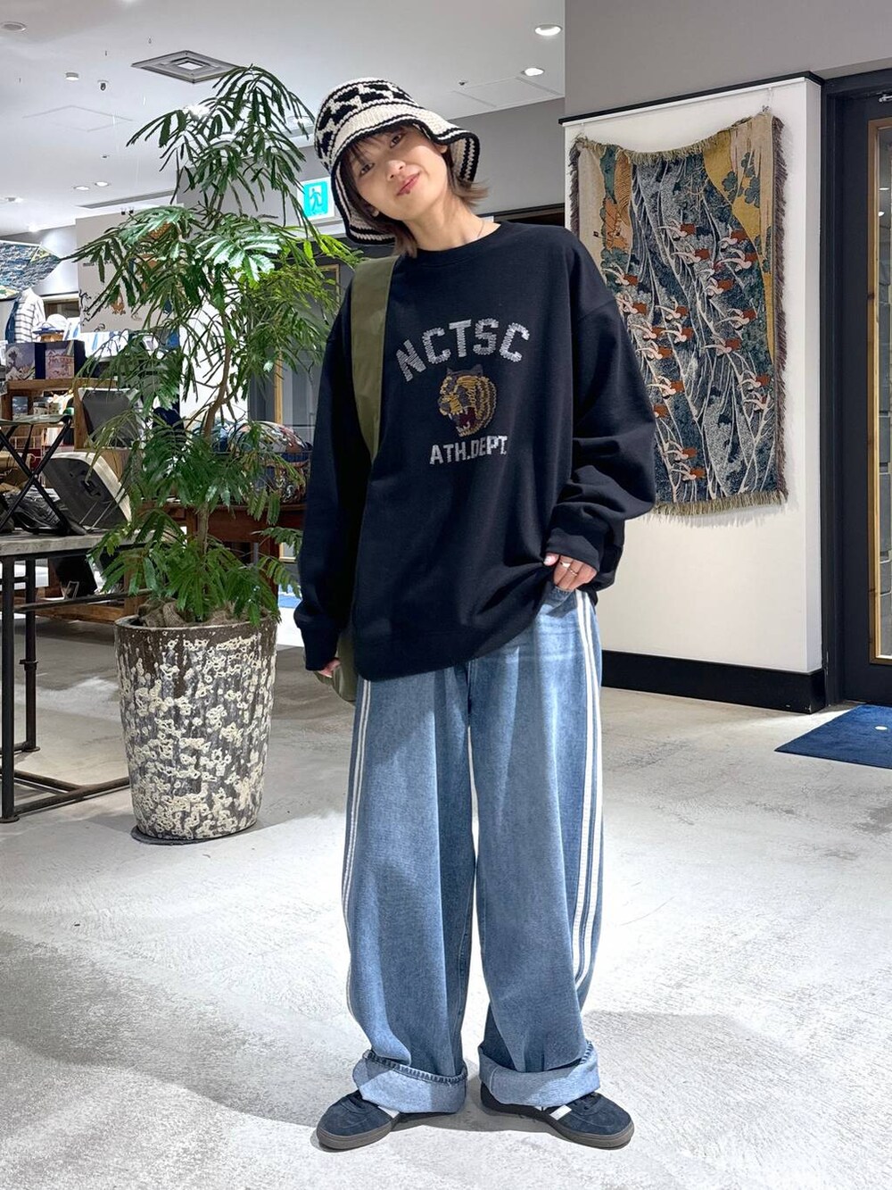 グリーン系のショルダーバッグ、ブラック系のスウェット、ホワイト系のハットを着用したメンズの冬コーディネートの2枚目の写真