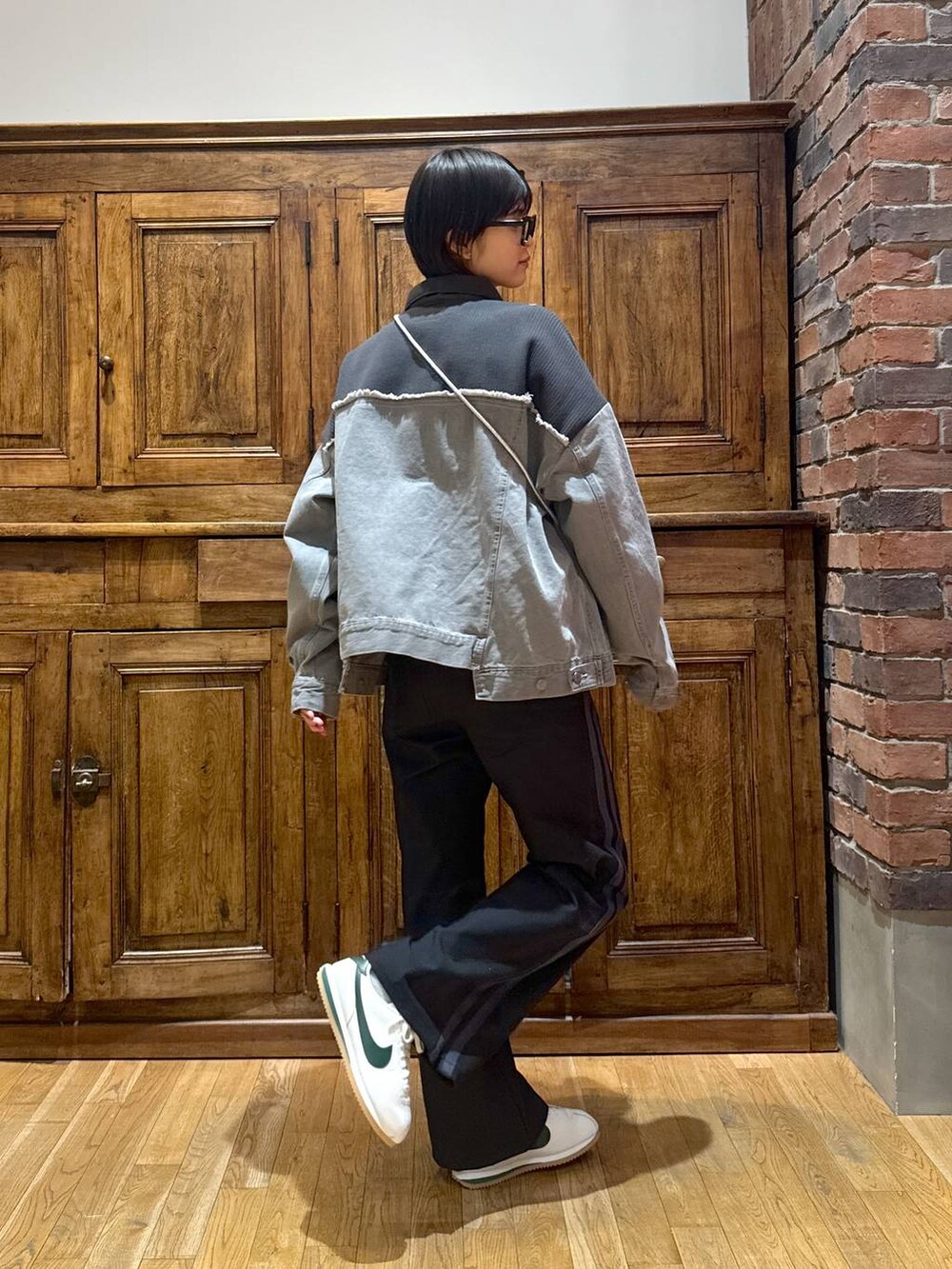 グレー系のデニムジャケット、ブラック系のショルダーバッグ、ブラック系のその他パンツを着用したレディースの冬コーディネートの2枚目の写真