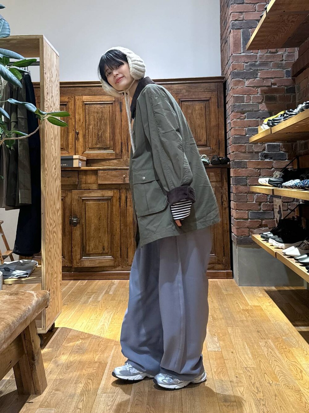 グレー系のスニーカー、グリーン系のブルゾン、ベージュ系のイヤーマフを着用したレディースの秋コーディネートの2枚目の写真
