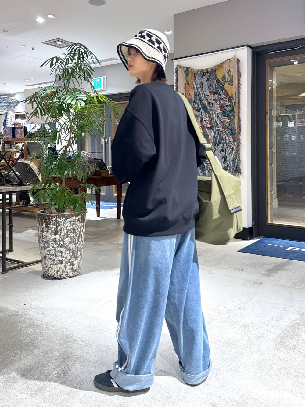 グリーン系のショルダーバッグ、ブラック系のスウェット、ホワイト系のハットを着用したメンズの冬コーディネートの3枚目の写真